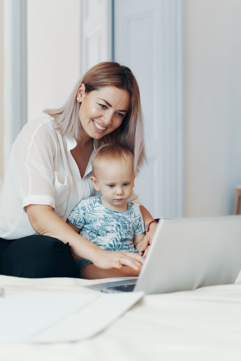 Smiling mother and toddler using a laptop together.